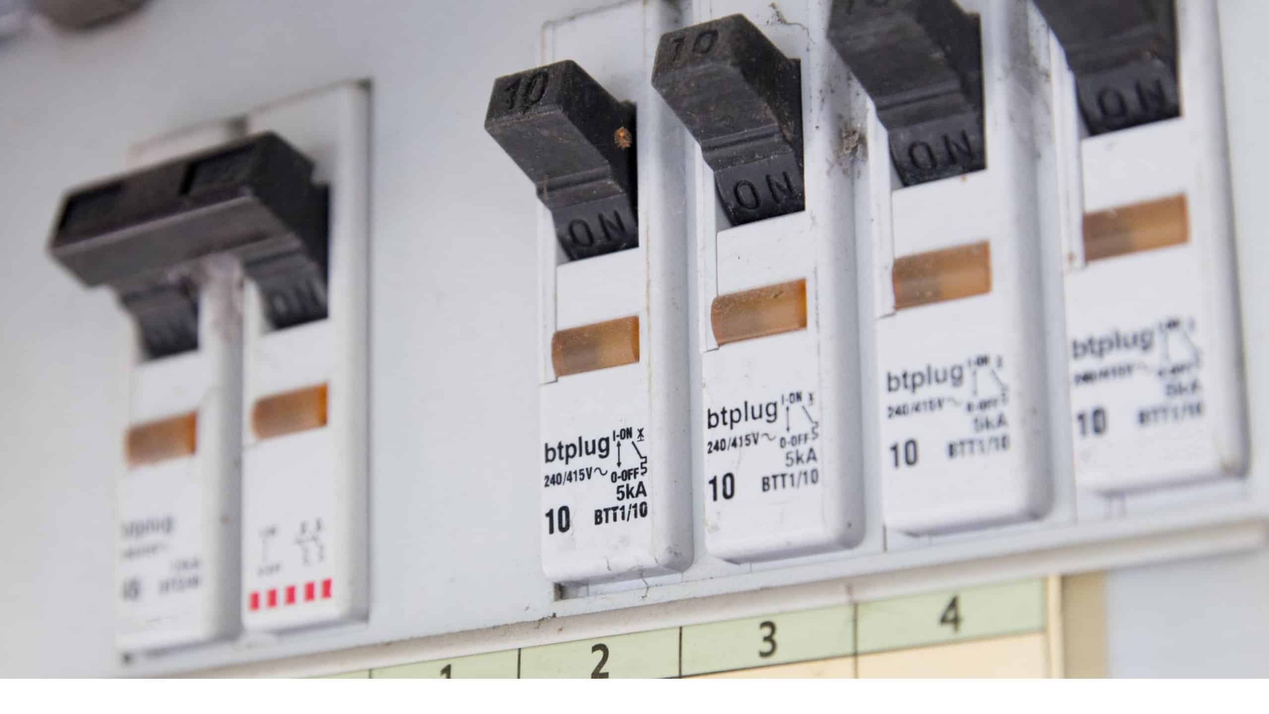 Electrical circuit breakers in the "on" position on a panel for charging electric vehicles.
