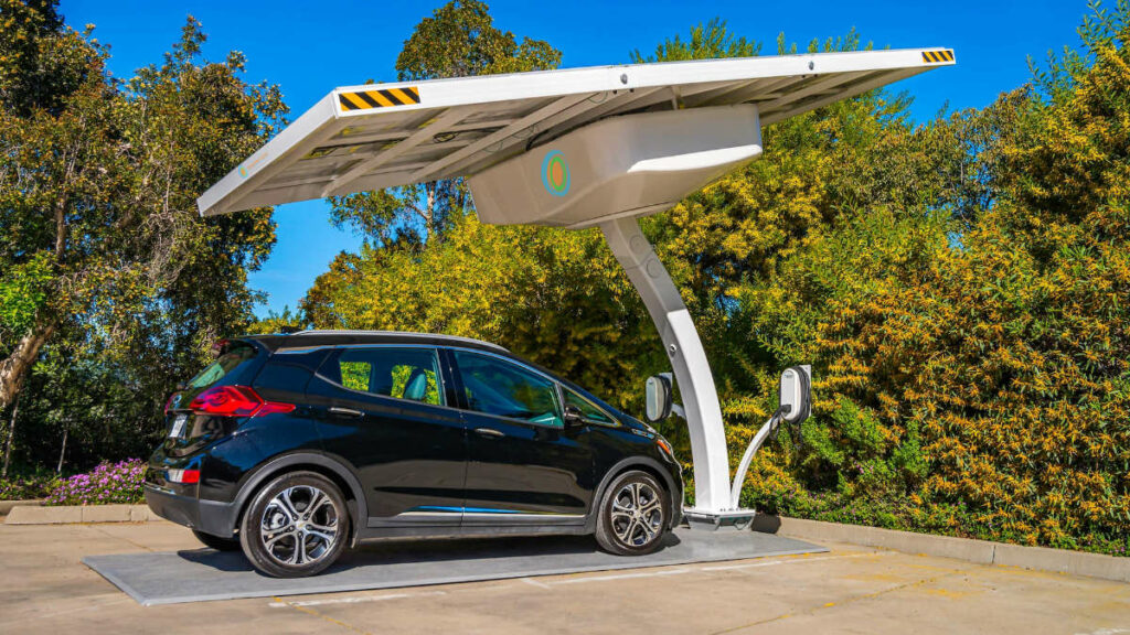 An electric car is parked and charging under a solar panel canopy at an Arizona commercial EV charging station.