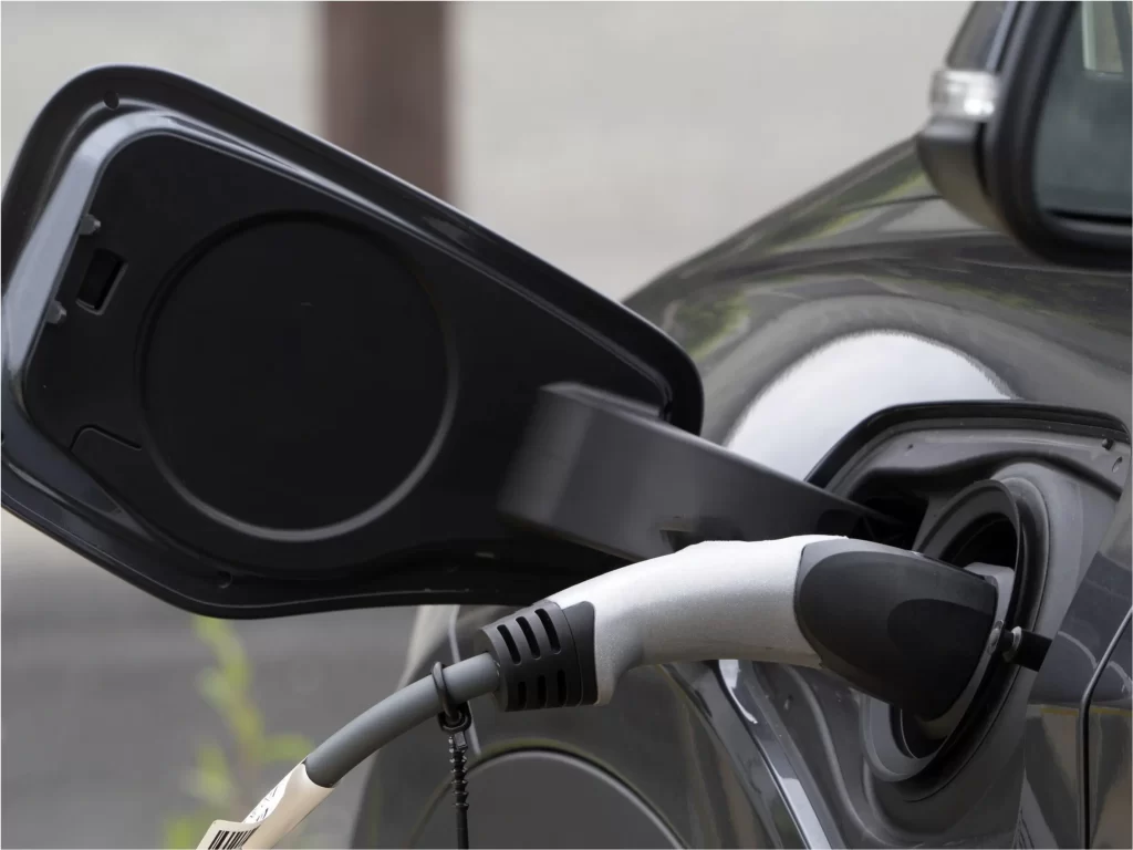 Electric car being charged with a power cable connected to its charging port.