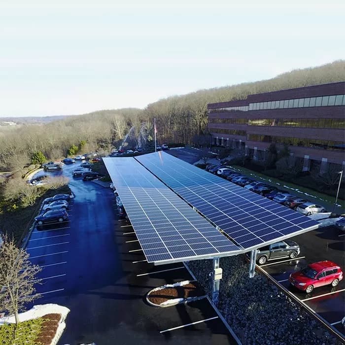 Solar panels and commercial EV charging stations installed over a parking lot adjacent to an office building in Arizona.
