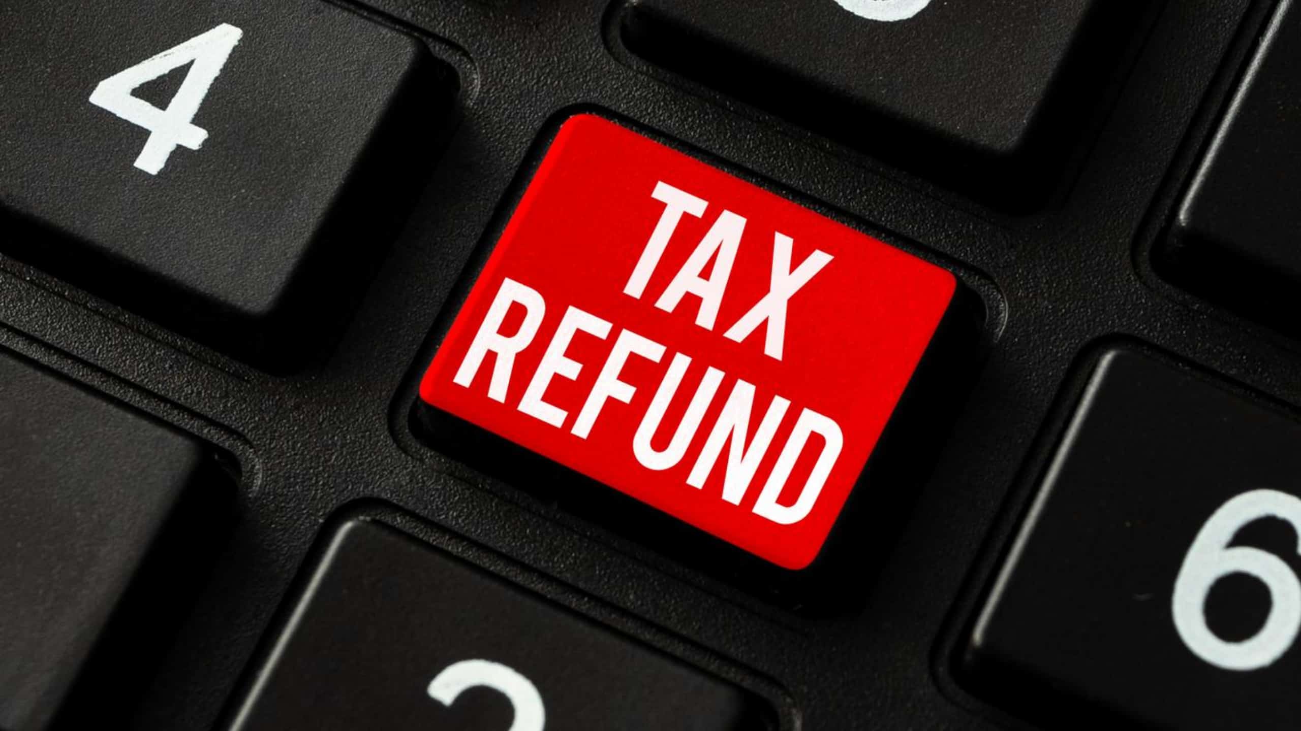 Red "tax refund" button on a computer keyboard among black keys.