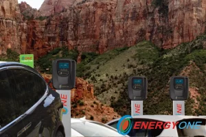 Electric cars parked at EV charging stations in a scenic mountainous area, with a prominent advertisement for Energy One charging service.