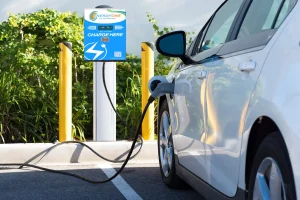 An electric car is plugged into a An EnergyOne Level 3 DCFC Fast charging station with the words "EnergyOne," reflecting the expertise of EV Charging Stations Experts. The vehicle is parked in a parking space with yellow poles in the background.