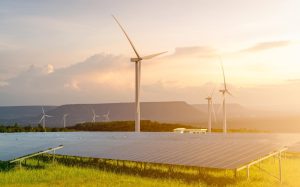 Renewables on the rise: Wind turbines and solar panels grace a green landscape under a clear sky, with the sun setting in the background, reflecting 2024's key highlights in energy generation data.